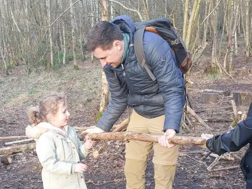 people carrying log man and child carrying a log in woodland